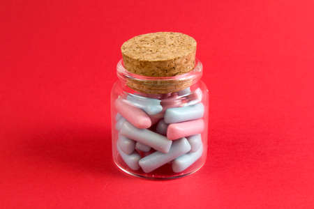 Jar full of blue and pink candies against bright red background close upの写真素材
