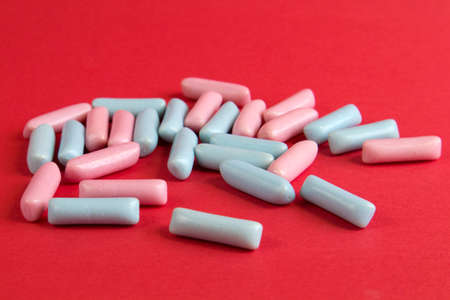 Bright blue and pink colorful candies scattered on red textured background front viewの写真素材