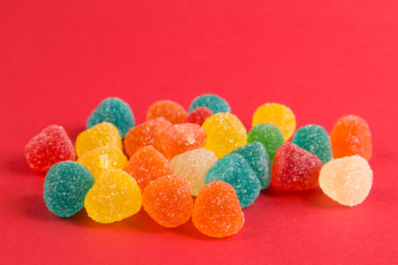 Bright colorful jelly candies in sugar on bright red background close upの写真素材