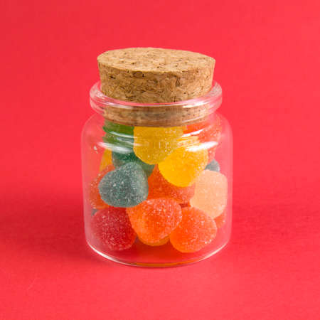 Bright colorful jelly candies in sugar on bright red background close up