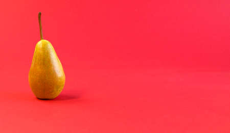 One juicy ripe yellow pear on bright red background close-up front view still lifeの写真素材