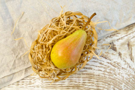Green yellow pears in brown wooden bowl on rough wooden background, top view still lifeの写真素材
