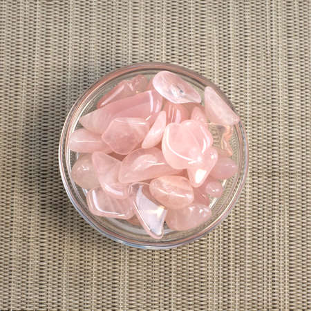 Several pieces of polished pink quartz on gray textured background. Minimal color still life...