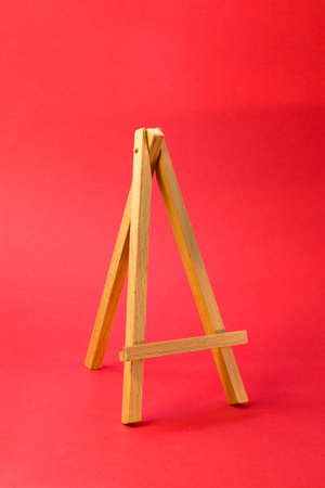 Easel for artists miniature on bright red background. Art minimal concept.の写真素材
