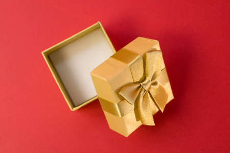 Open golden gift box with silk gold ribbon bow on bright pink background close upの写真素材
