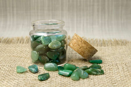 Macroshooting of natural mineral rock specimen - tumbled green aventurine gemstone on black...