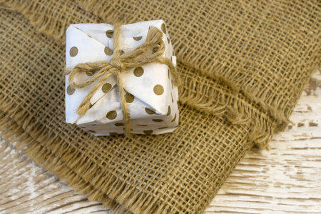 Closed golden white box with jute bow on rough linen background close upの写真素材