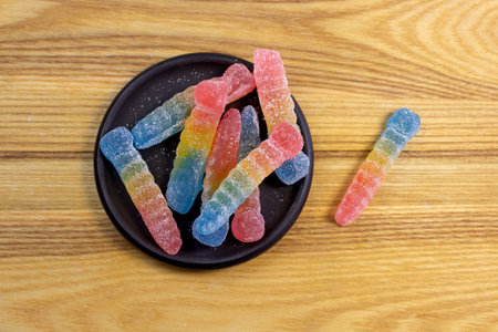 Bright colorful jelly candies in sugar on light beige wood background close upの写真素材