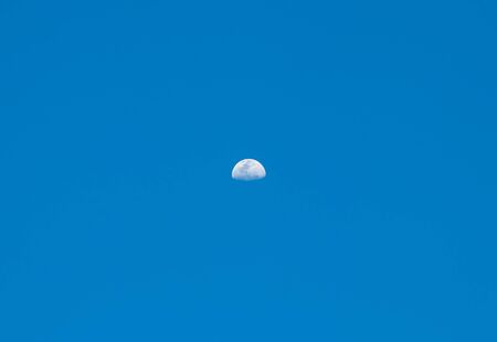 Not a full growing moon with craters against a blue sky at duskの写真素材