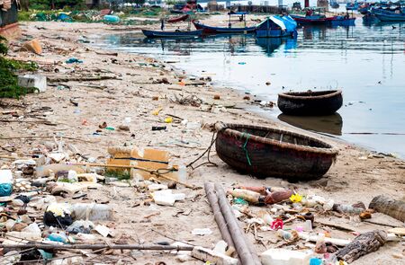Coast of the Vietnamese Sea with a fishing boat and a pile of garbage all over the area on the sand and the seaの写真素材