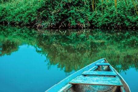 Reflection in the river of blue sky and green shrubs. On the right side the bow is blue.の写真素材