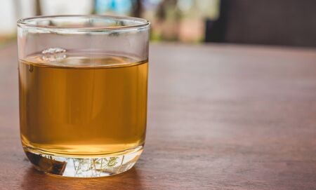 On a wooden table is a glass made of transparent glass, in it is green tea. Blurred backgroundの写真素材