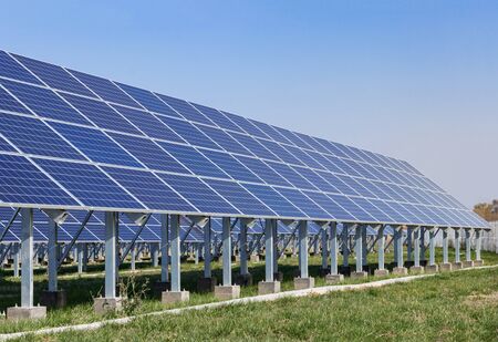 Four rows of solar panels at the station. Background blue sky and green grassの写真素材