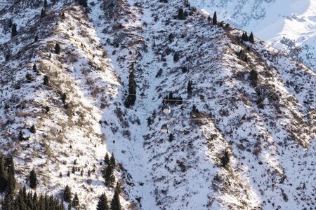 Cabins of the cable car over the precipice. Background big snowy mountains with Christmas treesの写真素材