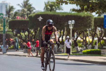 NHA TRANG, VIETNAM - JULY 14, 2019: Tony Tran a triathlon competitor in Challenge Vietnam rides a Bicycle along Tran Phu streetのeditorial素材