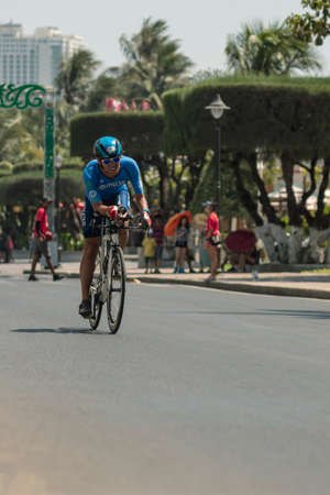 NHA TRANG, VIETNAM - JULY 14, 2019: Tu Hoang a triathlon competitor in Challenge Vietnam rides a Bicycle along Tran Phu streetのeditorial素材