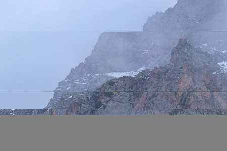 The peak of a mountain cliff in the fog. Against the backdrop of a foggy skyの写真素材