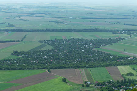 The village is densely overgrown with trees among agricultural fields. Top viewの写真素材
