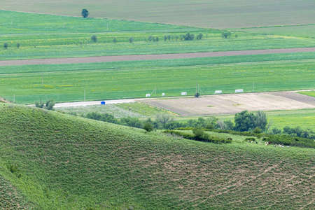The ridge of a mountain hill in vegetation against the background of agricultural fields and a country roadの写真素材
