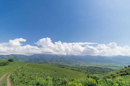 View of mountain hills and valley on a sunny day with clouds and blue skyの写真素材