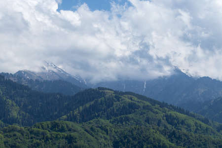 Over the green hills, clouds cover the mountain topsの写真素材