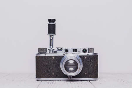 An old retro self-timer camera stands on a wooden table. The background is whiteの写真素材
