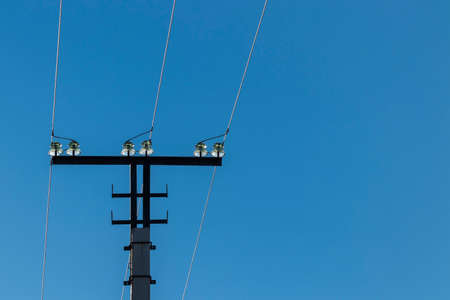 Upper part of a three-phase transmission line tower with insulators. Against the background of the blue sky.の写真素材
