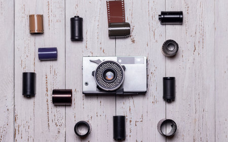 An old retro camera and pieces of photographic film lie on a wooden table. view from above.
