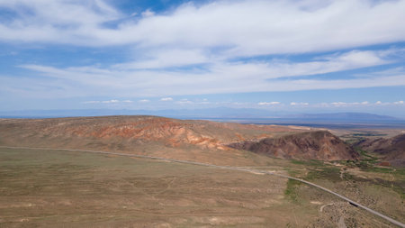 The desert area and the mountains are separated by a road. The view from the droneの写真素材