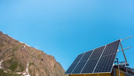Solar panels are installed on the facade of a house in the mountains. Sunny day