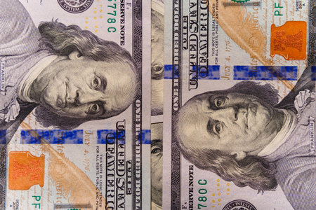 Oppositely placed $100 bills with a portrait of Benjamin Franklin