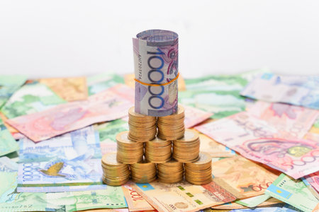 A folded 10,000 tenge banknote stands on coins with a rubber band. Currency devaluation
