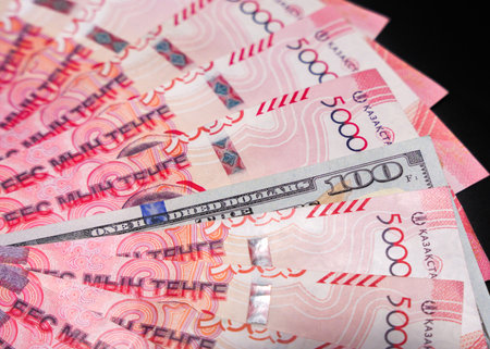 100 dollars among a fan of 5000 tenge bills. Paper money from circulation