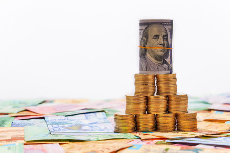 A folded $100 bill stands on tenge coins. Money exchangeの写真素材