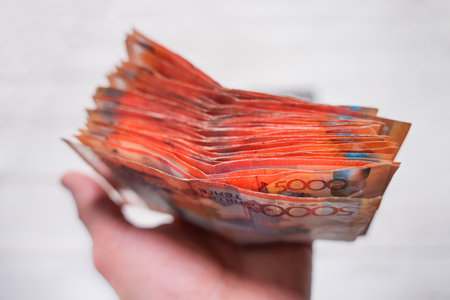 A stack of large tenge banknotes in hand. Transferring money