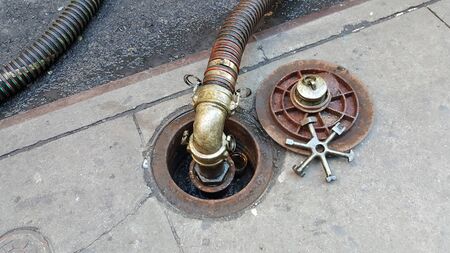 oil fuel truck piped iin delivery service. city walkway open cap and lug wrench
