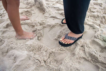 Mother and daughter's feet on a sandy beachの写真素材