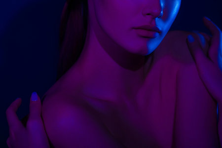 Woman on pink blue neon background. Hands and lips close-up. Anonymous beauty portrait.の写真素材