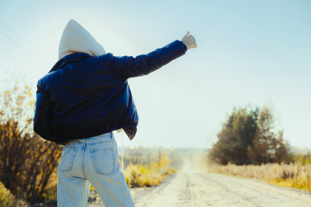Woman is hitchhiking on background of road. Travelの写真素材