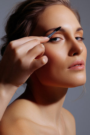 Eyebrow brushing on white adult model in close-up. Radiant skin, natural shades and neatness in makeupの写真素材