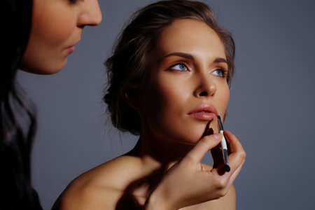 Makeup artist paint lips of model. Makeup in natural shades, backstage workの写真素材