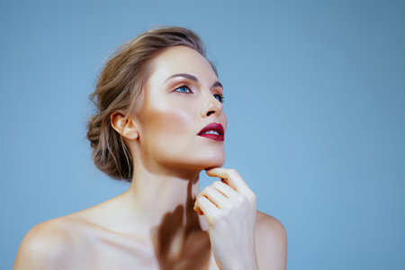 White beautiful blond woman on blue background. Fashion makeup with red lipstick and manicureの写真素材