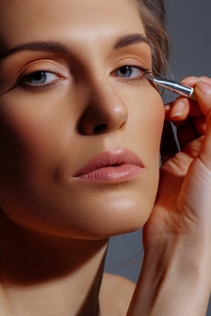 Eyebrow brushing on white adult model in close-up. Radiant skin, natural shades and neatness in makeupの写真素材