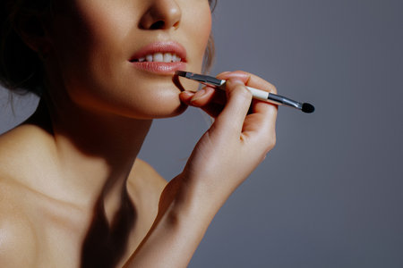 Makeup artist puts lipstick on lips of model. Nude makeup close-up. Backstage work, anonymous portraitの写真素材