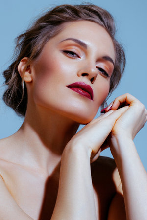 White beautiful blond woman on blue background. Fashion makeup with red lipstick and manicureの写真素材