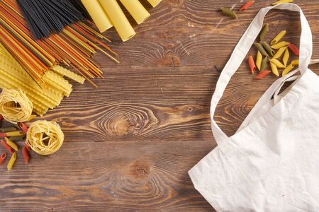 Multicolored pasta on wooden background with copyspace and bagの写真素材