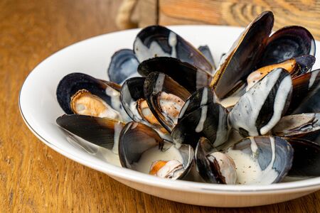 mussels in blue cheese on white plate on tableの写真素材