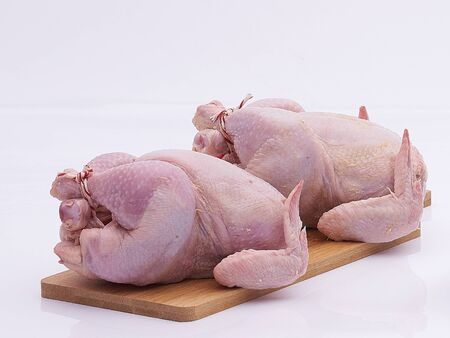 two chickens raw on wooden plate on white isolatedの写真素材