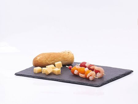 shrimps, cherry tomatoes and cheese on black plate on whiteの写真素材