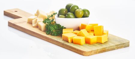 two cheeses and olives on wooden plate on white isolatedの写真素材